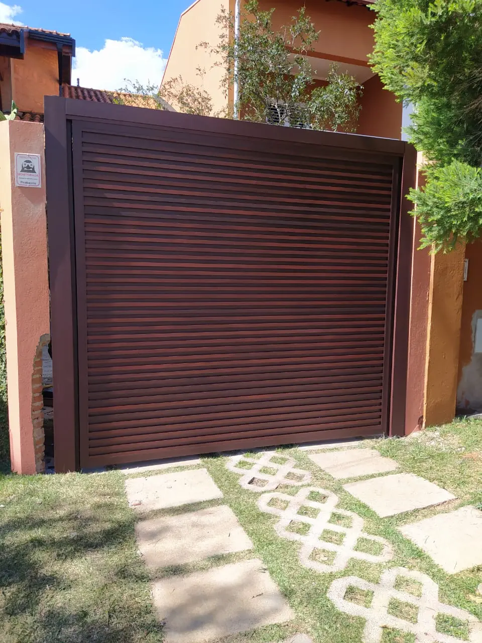 Portão de alumínio amadeirado, acabamento imitando madeira, instalado em residência